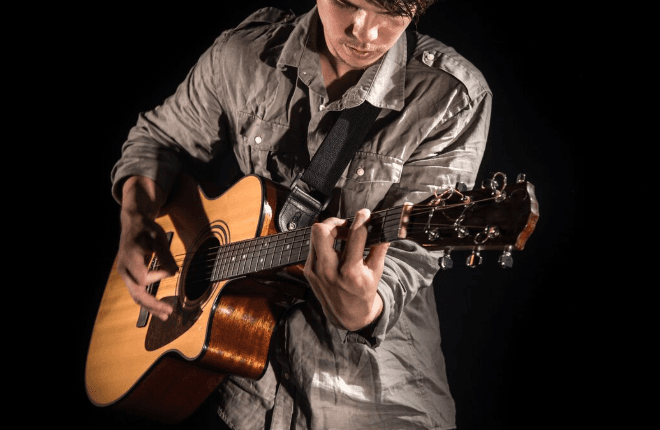 Manos y cuerpo de guitarra acústica en primer plano