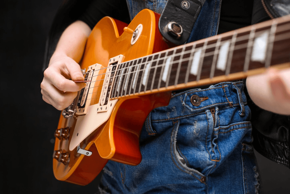 Detalle de una guitarra Les Paul sunburst mientras se toca con púa