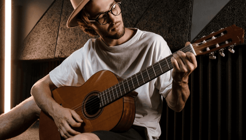 Persona con guitarra acústica en un entorno doméstico