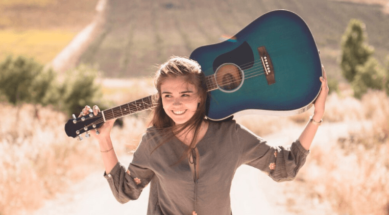 Persona tocando una guitarra acústica al aire libre