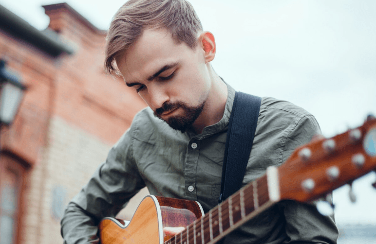 Persona tocando acústica en un entorno natural