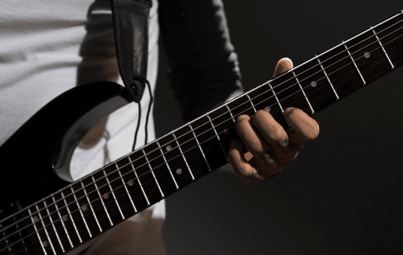 Manos en el diapasón de una guitarra eléctrica