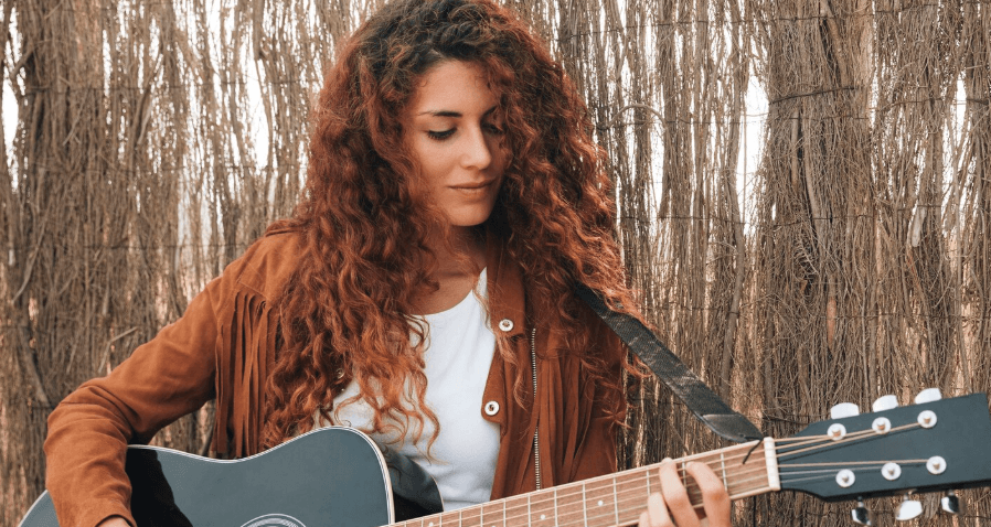 Persona practicando con guitarra acústica en casa