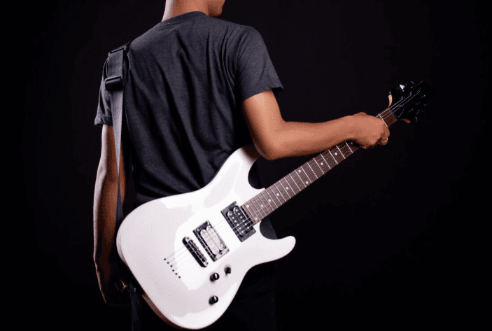 Primer plano de una guitarra eléctrica blanca en uso