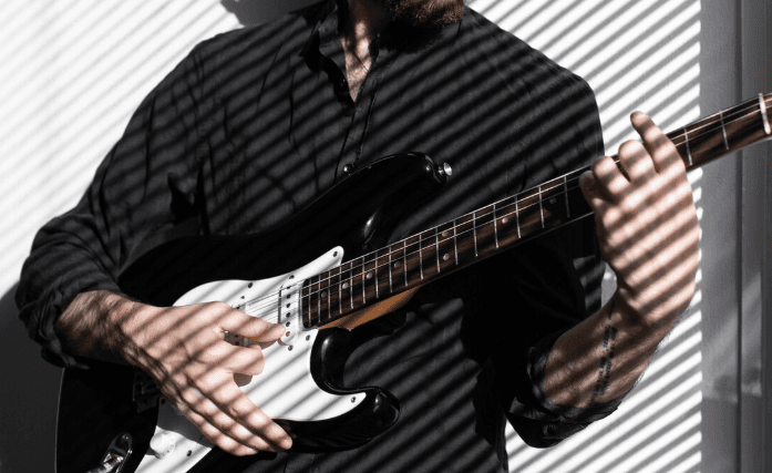 Manos sobre el diapasón de una guitarra acústica