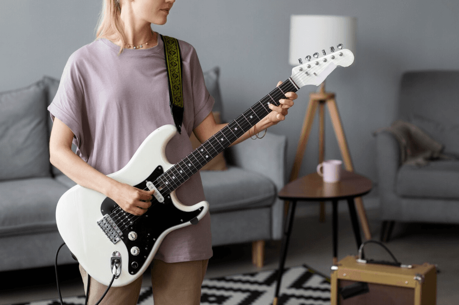 Guitarrista con guitarra eléctrica blanca en un salón luminoso