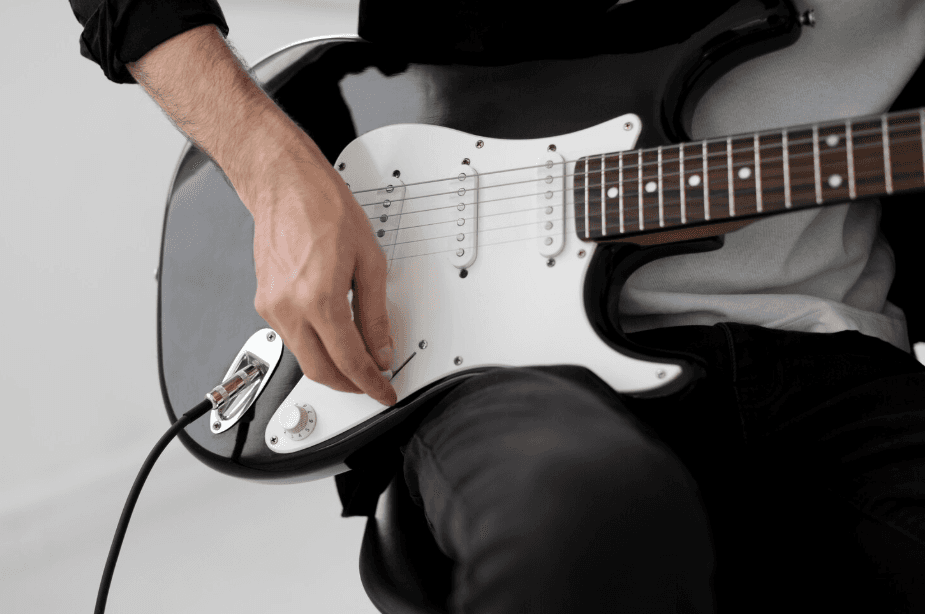 Detalle de una guitarra eléctrica negra con golpeador blanco